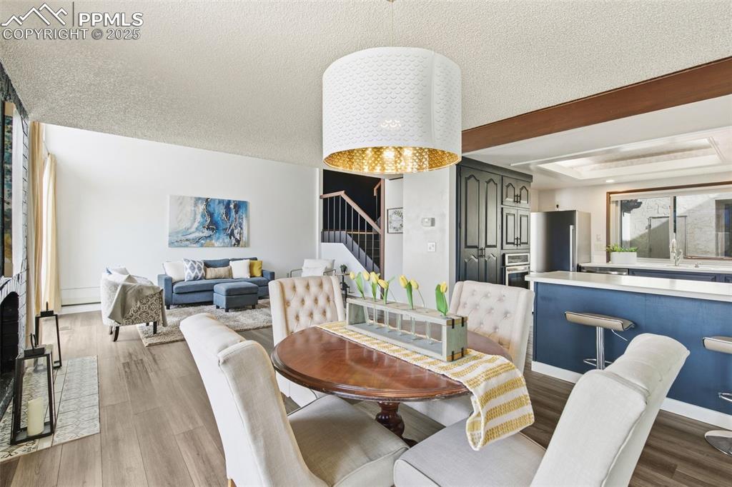 Image 18 of 45: Dining room featuring stairs, a textured ceiling, dark wood-style flooring,