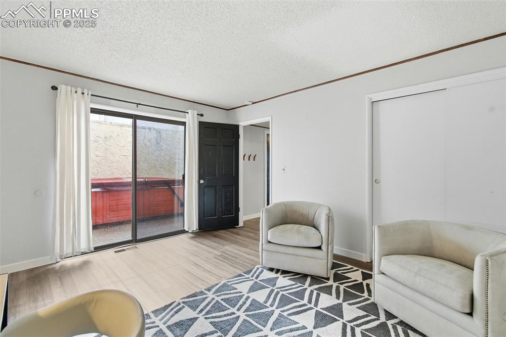 Image 21 of 45: Living area with wood finished floors, a textured ceiling, and ornamental m