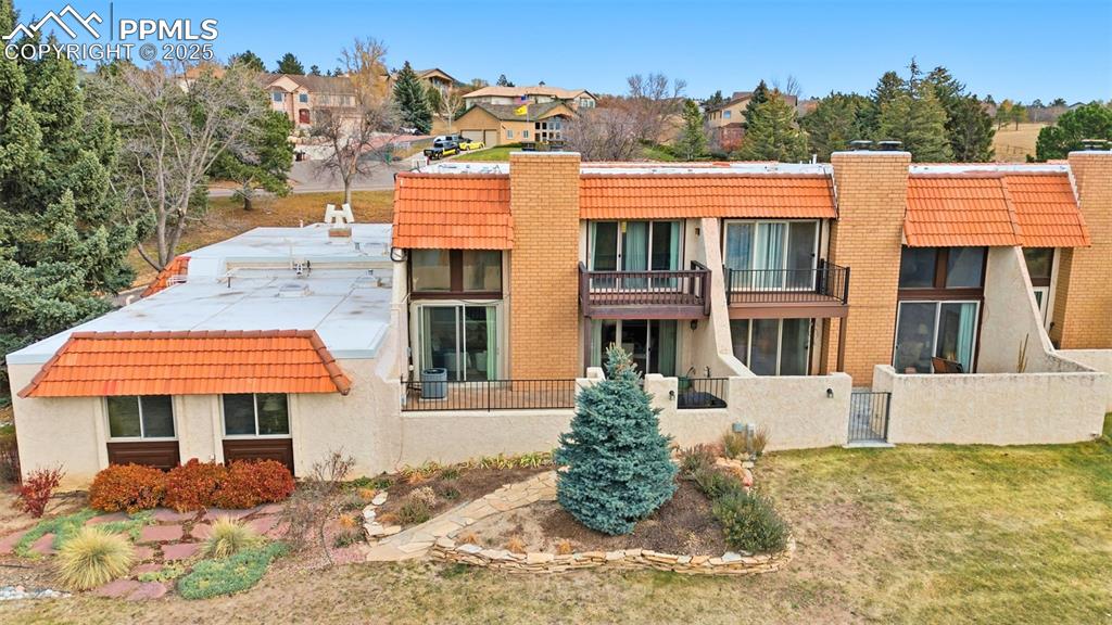 Image 38 of 45: Back of house featuring a chimney, a balcony, and stucco siding