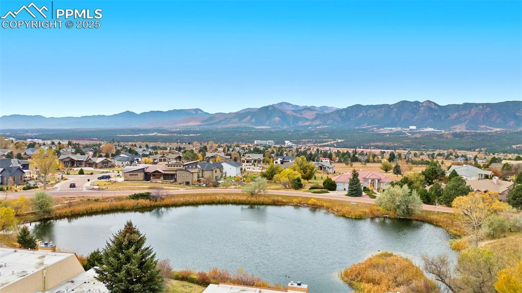 Image 4 of 45: Aerial perspective of neighborhood pond with a mountain view
