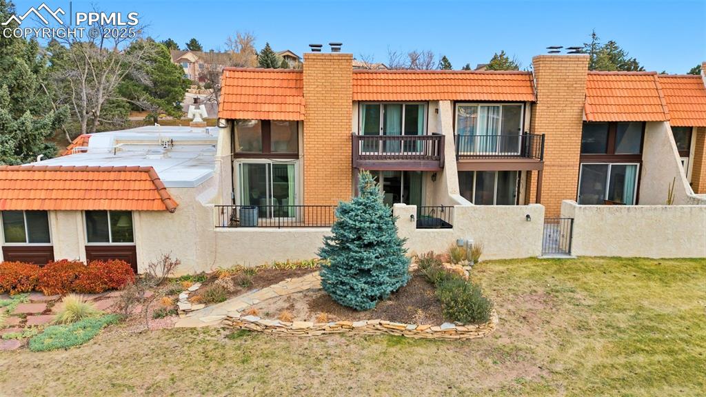 Image 41 of 45: Back of property featuring a tiled roof, a chimney, a balcony, and a gate