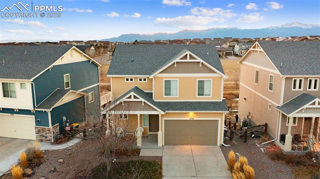 Caption: Craftsman-style home with a residential view, an attached garage, a shingled roof, a mountain view, 