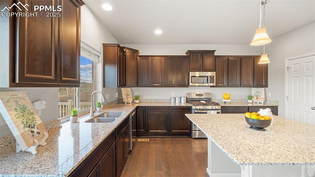 Image 12 of 48: Kitchen featuring appliances with stainless steel finishes, dark brown cabi