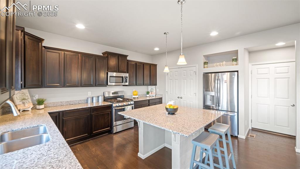 Image 15 of 48: Kitchen with appliances with stainless steel finishes, pendant lighting, da