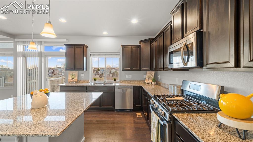 Image 16 of 48: Kitchen with appliances with stainless steel finishes, light stone counters