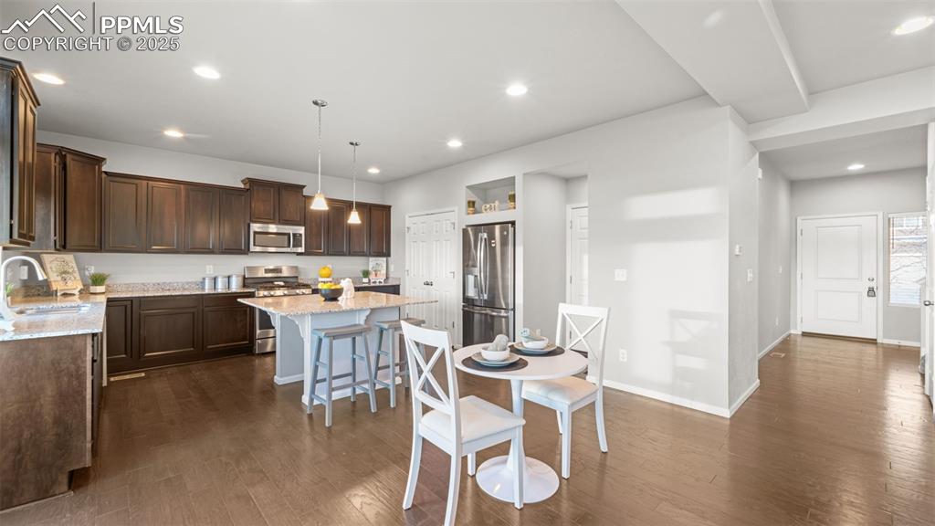 Image 18 of 48: Kitchen featuring light stone counters, decorative light fixtures, a breakf