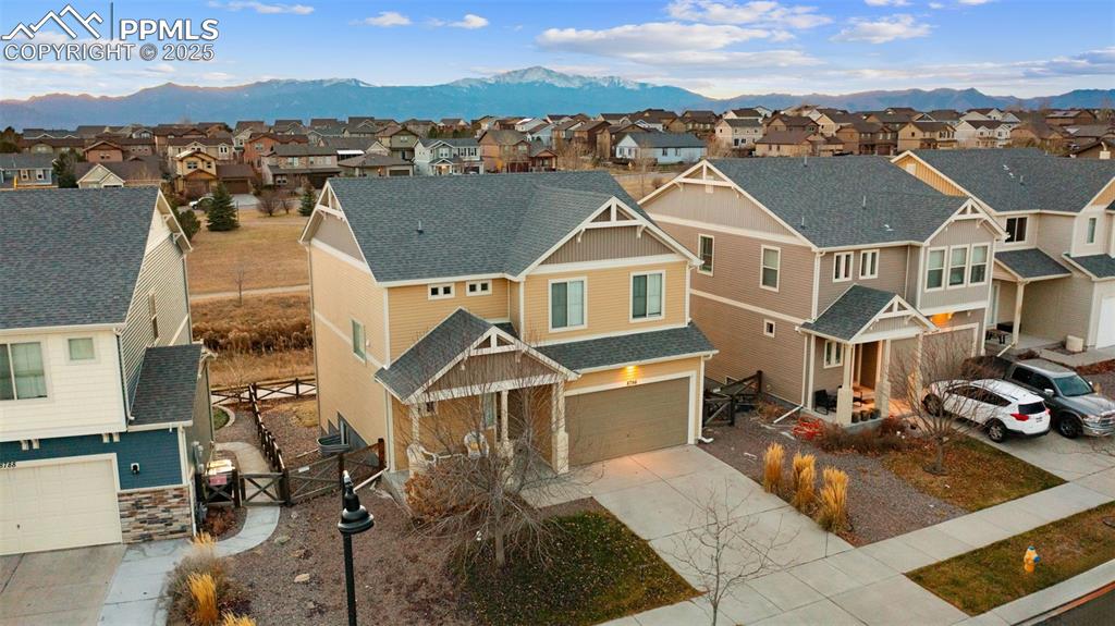 Image 2 of 48: View of front of home with a shingled roof, driveway, and a residential vie