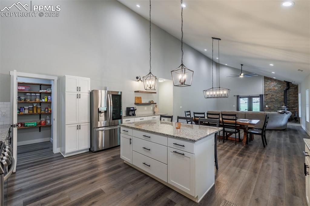 Image 11 of 38: Kitchen featuring high vaulted ceiling, stainless steel fridge, white cabin