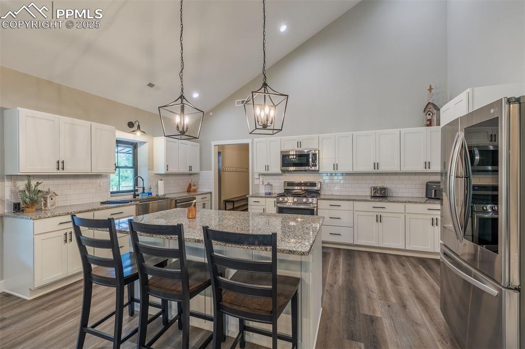 Image 13 of 38: Kitchen featuring appliances with stainless steel finishes, high vaulted ce