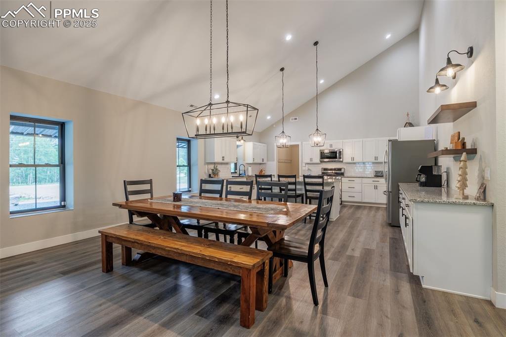 Image 16 of 38: Dining area with high vaulted ceiling, wood finished floors, a chandelier, 