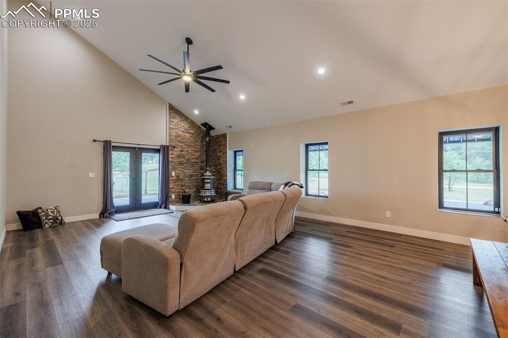 Image 17 of 38: Living area with a wood stove, a ceiling fan, high vaulted ceiling and walk