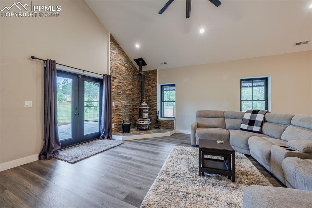 Image 18 of 38: Living room featuring a wood stove, wood finished floors, high vaulted ceil