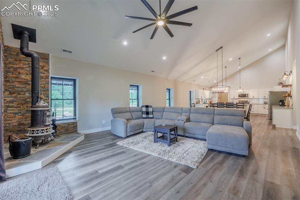 Image 19 of 38: Living room featuring a wood stove, a ceiling fan, light wood-style floors,