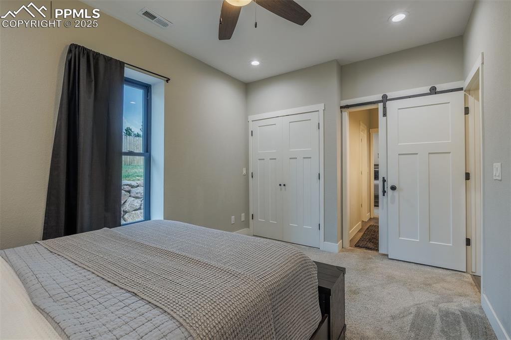 Image 30 of 38: Bedroom with light carpet, a barn door, recessed lighting, and a ceiling fa