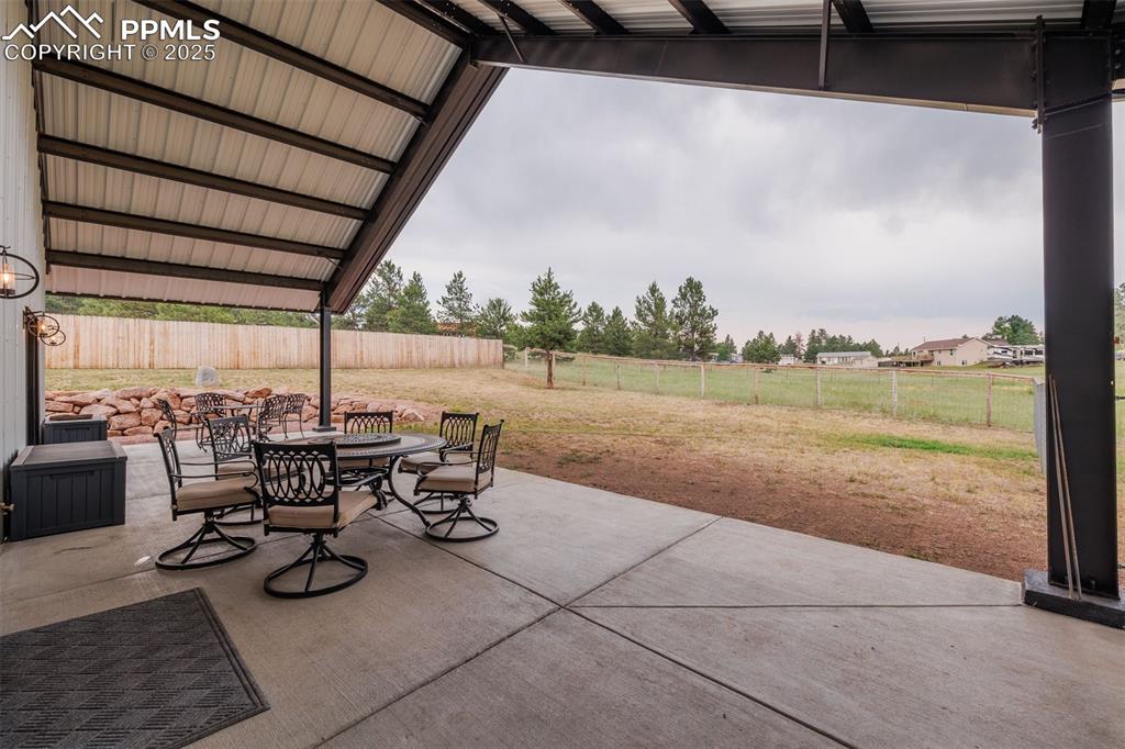 Image 34 of 38: Fenced backyard with covered patio. this patio furniture is not included