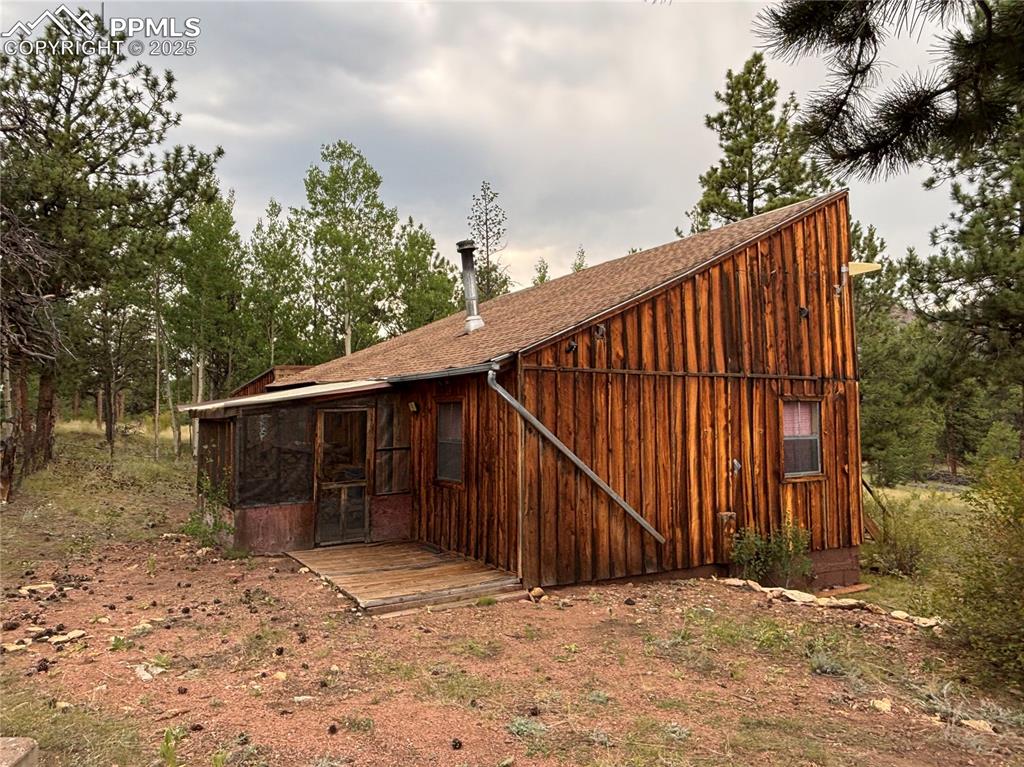 Image 12 of 40: Back of property with a sunroom, a shingled roof, board and batten siding,