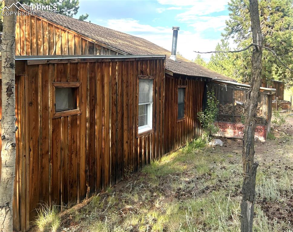 Image 14 of 40: View of side of home with a shingled roof and board and batten siding