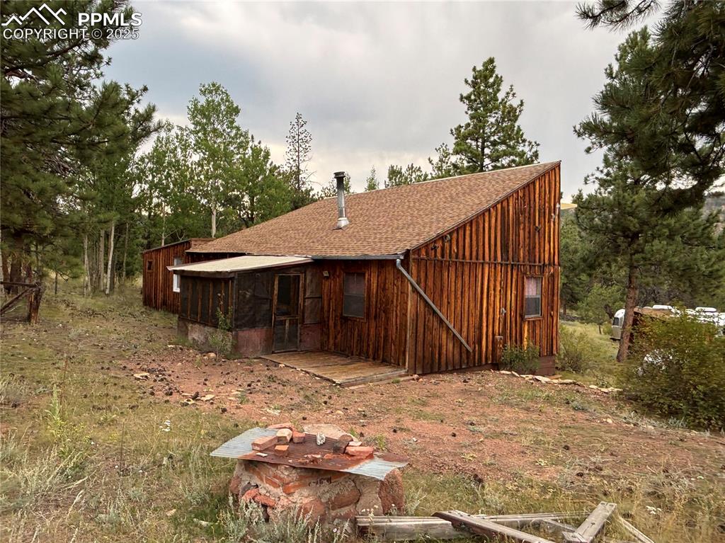 Image 5 of 40: Back of property with a sunroom, a shingled roof, and board and batten sidi