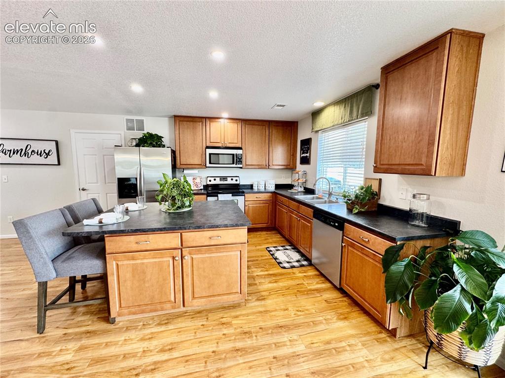 Image 10 of 36: Kitchen featuring wood-finish flooring, a central island with integrated se