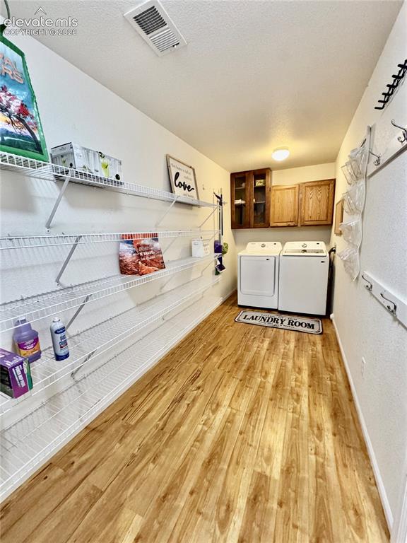 Image 12 of 36: Dedicated laundry area with wood-finish flooring, overhead lighting, and bu