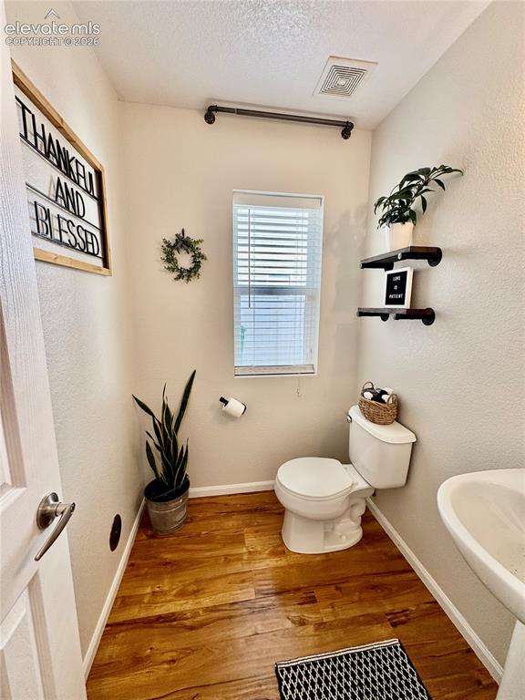 Image 14 of 43: Powder room featuring wood-finish flooring, a contemporary toilet, and a pe