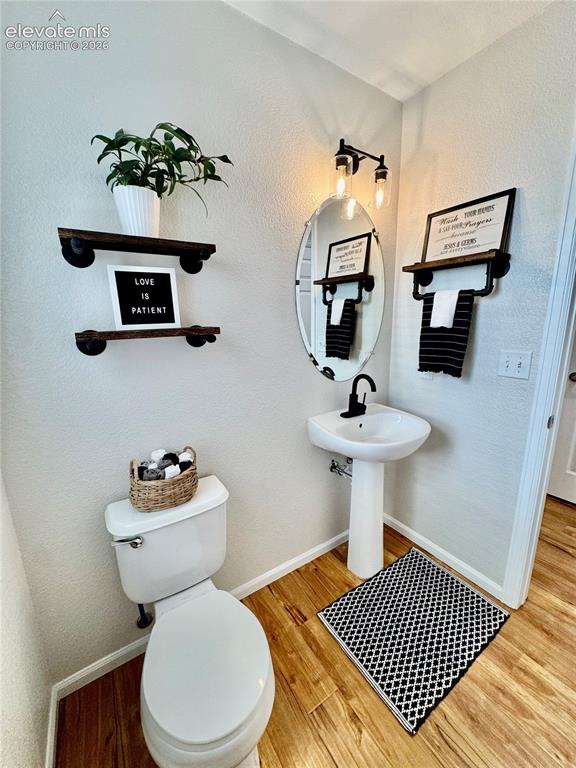 Image 15 of 43: Powder room featuring wood-finish flooring, a white pedestal sink with a ma