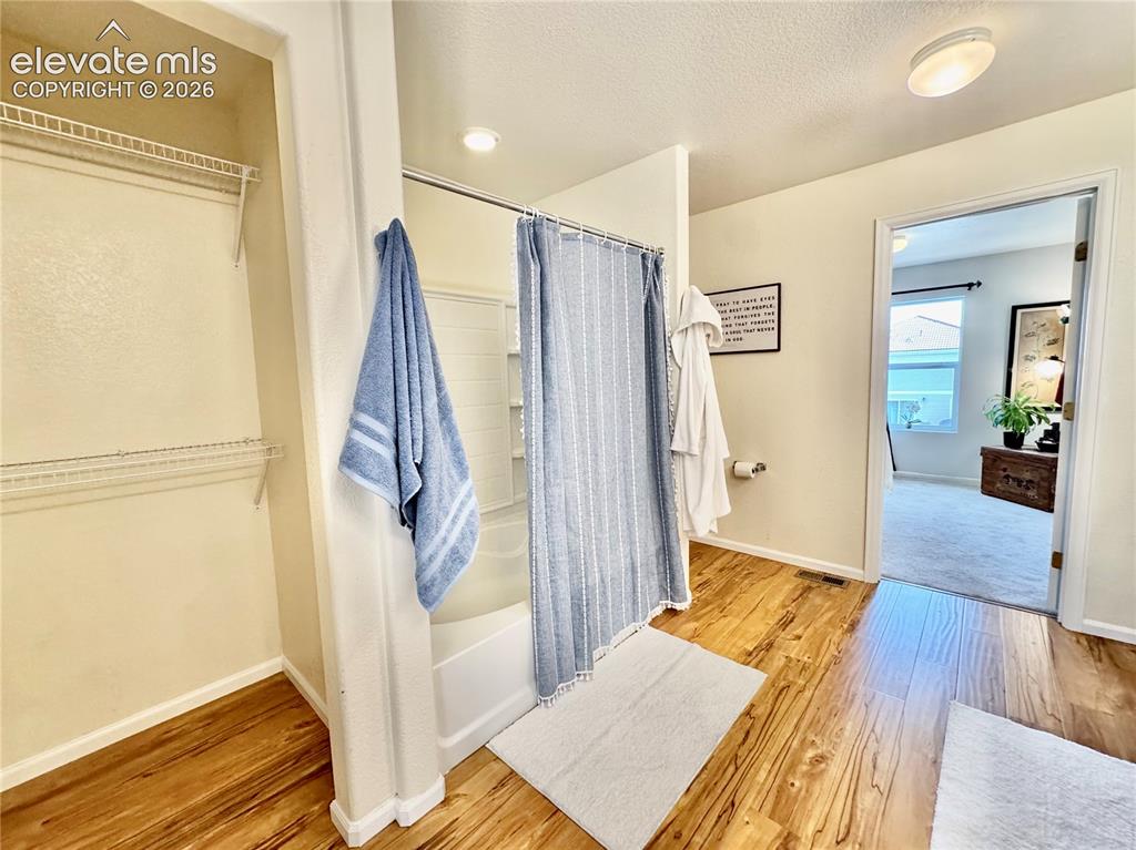 Image 21 of 43: Bathroom featuring wood-finish flooring, a combination shower and tub, and