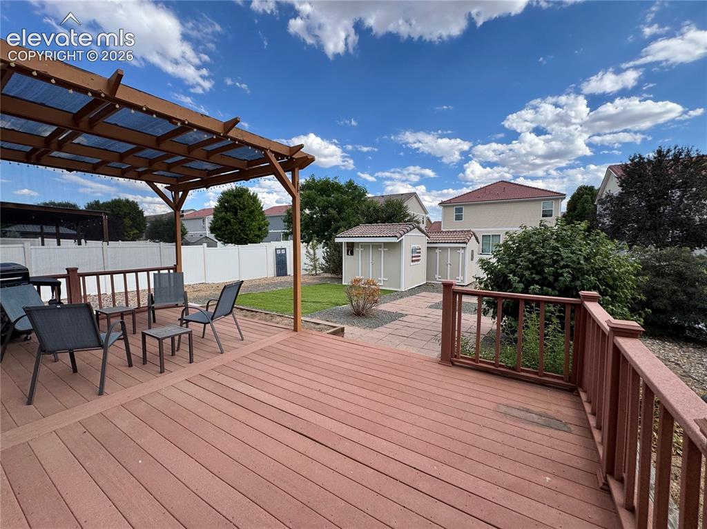 Image 31 of 36: Expansive rear deck with a wood pergola featuring a translucent roof, exten