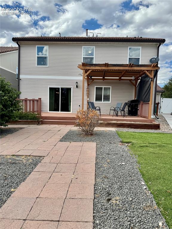 Image 33 of 36: Rear exterior featuring light-toned siding, a multi-level wood deck, a slid
