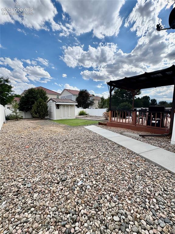 Image 35 of 36: Expansive backyard featuring a large gravel area, a section of green lawn, 