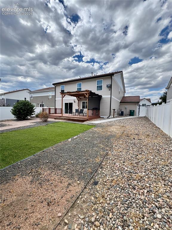 Image 36 of 36: Rear exterior featuring light-colored siding, a wooden deck with a pergola,