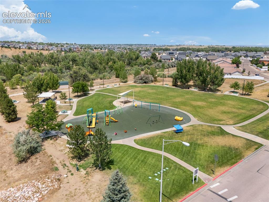 Image 41 of 43: Community green space featuring a playground, paved walking paths, a covere