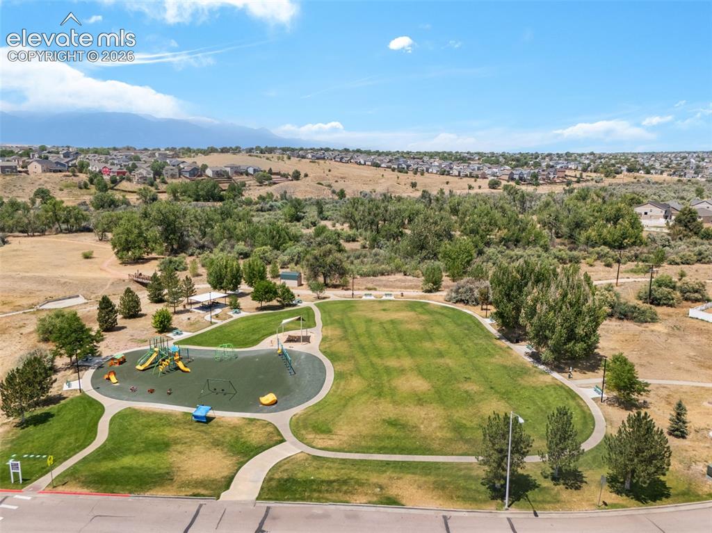 Image 42 of 43: Expansive green space featuring a playground with multiple slides, paved pa