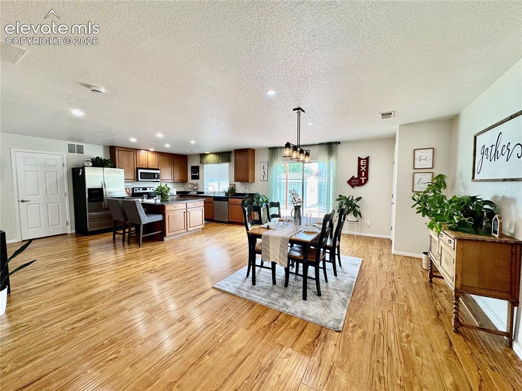 Image 5 of 36: Open-concept living space featuring wood-finish flooring, recessed lighting