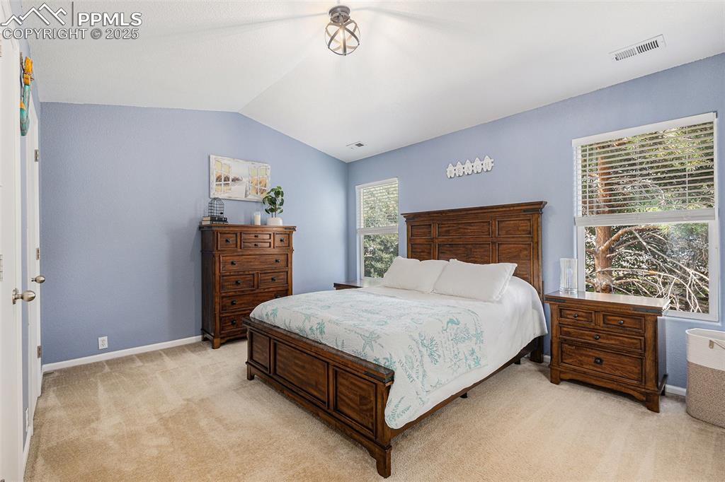 Image 14 of 24: Bedroom featuring light colored carpet, vaulted ceiling with vaulted ceilin
