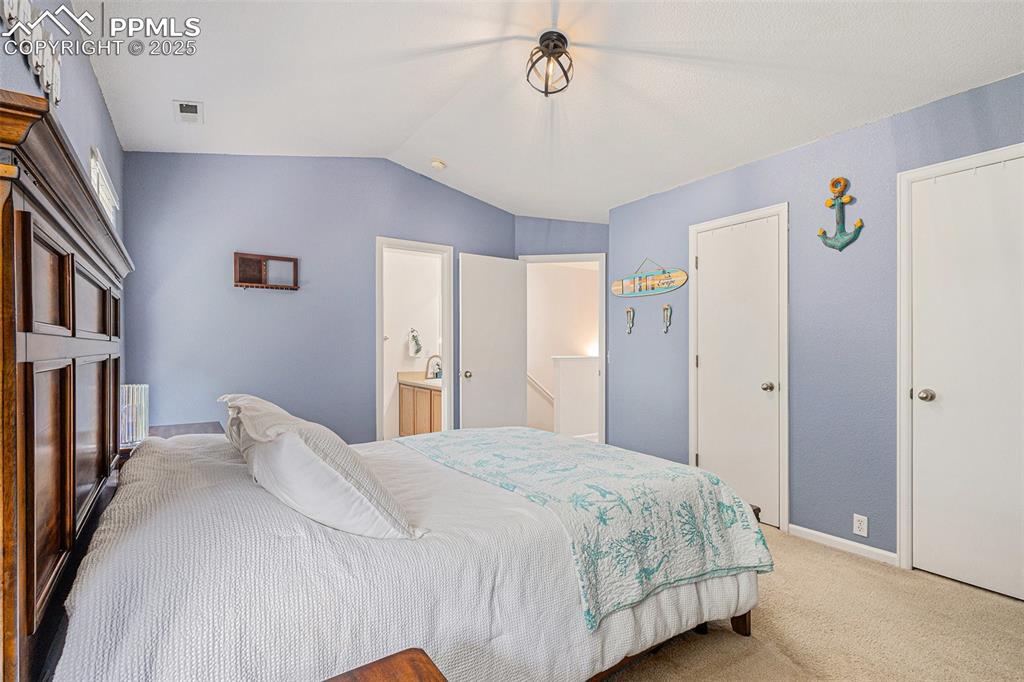 Image 15 of 24: Bedroom featuring light colored carpet, vaulted ceiling with vaulted ceilin