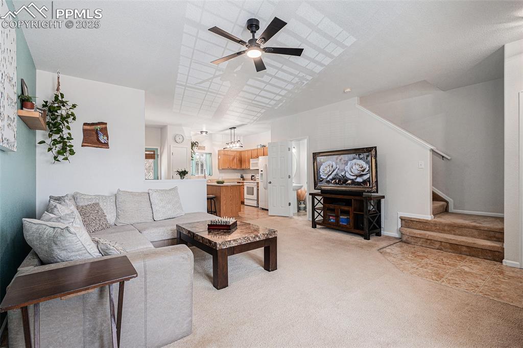 Image 6 of 24: Living area with light carpet, stairway, and updated lighting and ceiling f