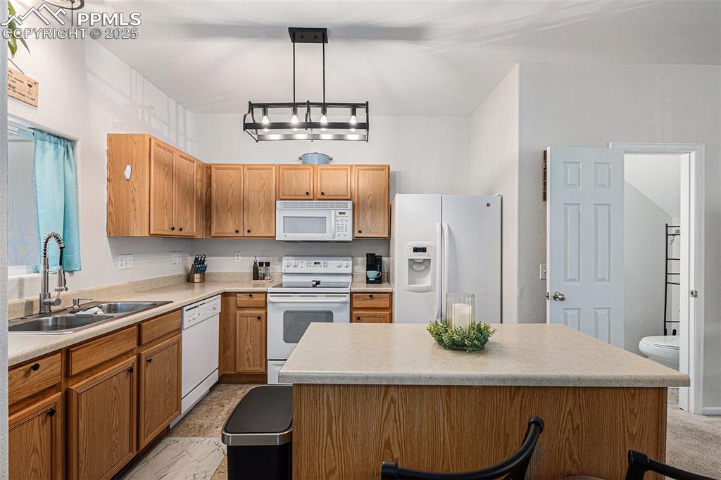 Image 9 of 24: Kitchen featuring white appliances, updated lighting, a kitchen island, a k