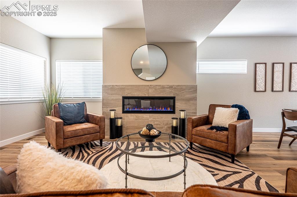 Image 4 of 43: Living area featuring baseboards, wood finished floors, and a tiled firepla