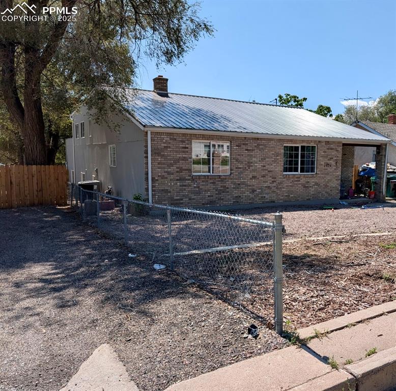Caption: View of side of home with brick siding, a metal roof, and a chimney