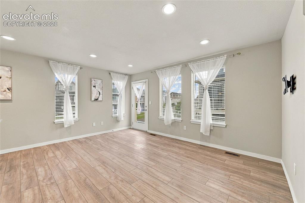 Image 10 of 30: Recessed lighting, wood-finish flooring, multiple windows, and a rear door 