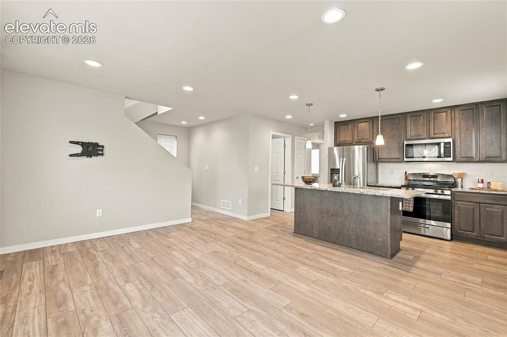 Image 11 of 30: Open-concept space featuring wood-finish flooring, recessed lighting, and a