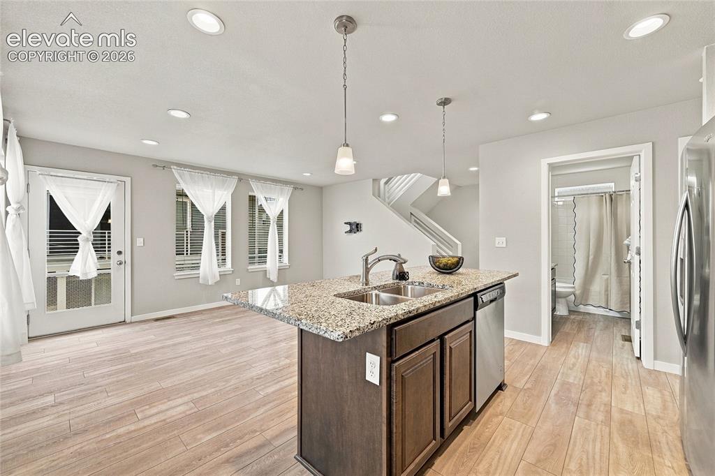 Image 12 of 30: Kitchen island with granite countertop, double basin sink, and stainless st