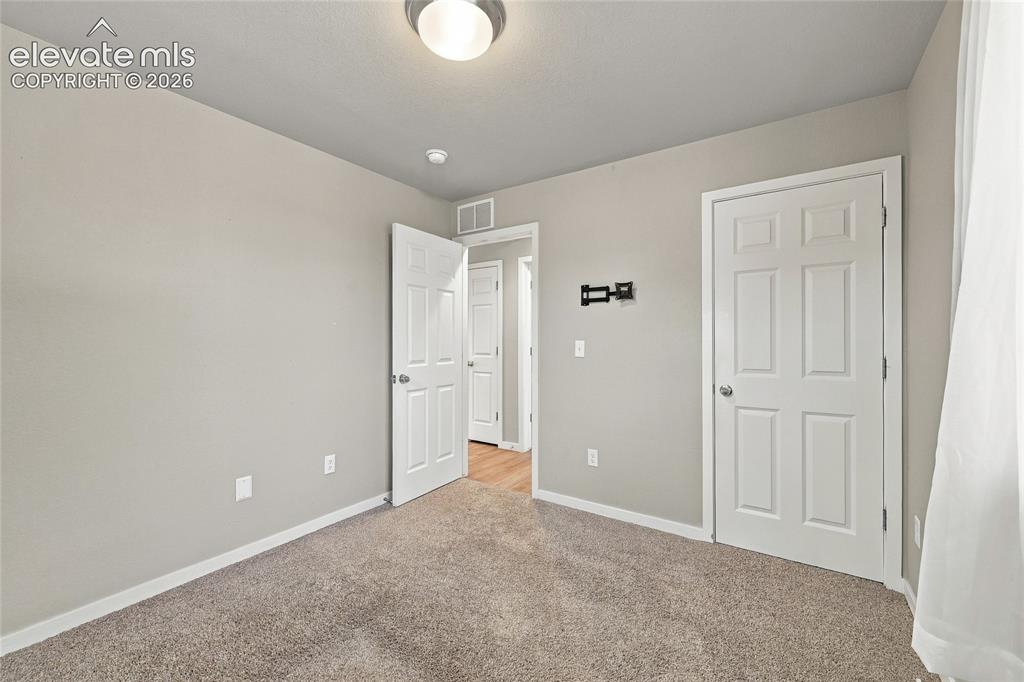 Image 14 of 30: Neutral wall paint, carpeted flooring, white trim, paneled doors