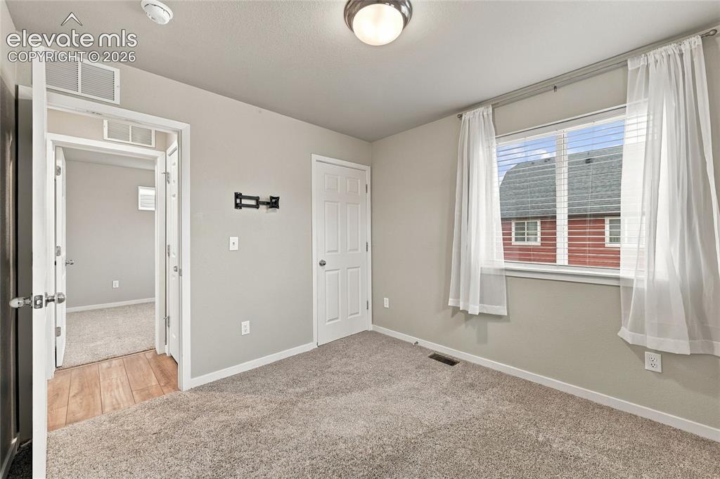 Image 15 of 30: Carpeted room with a window, ceiling-mounted light fixture, and white trim