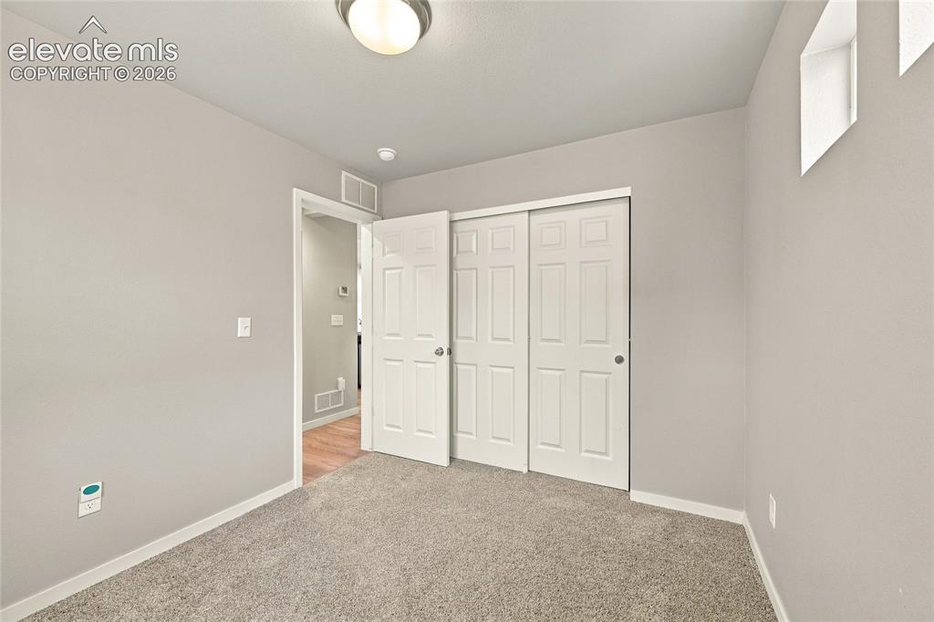 Image 16 of 30: Carpeted room with light neutral wall paint, two-panel bifold closet doors,