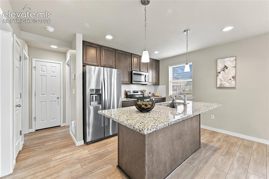 Image 2 of 30: Kitchen featuring an island with a granite countertop, stainless steel appl