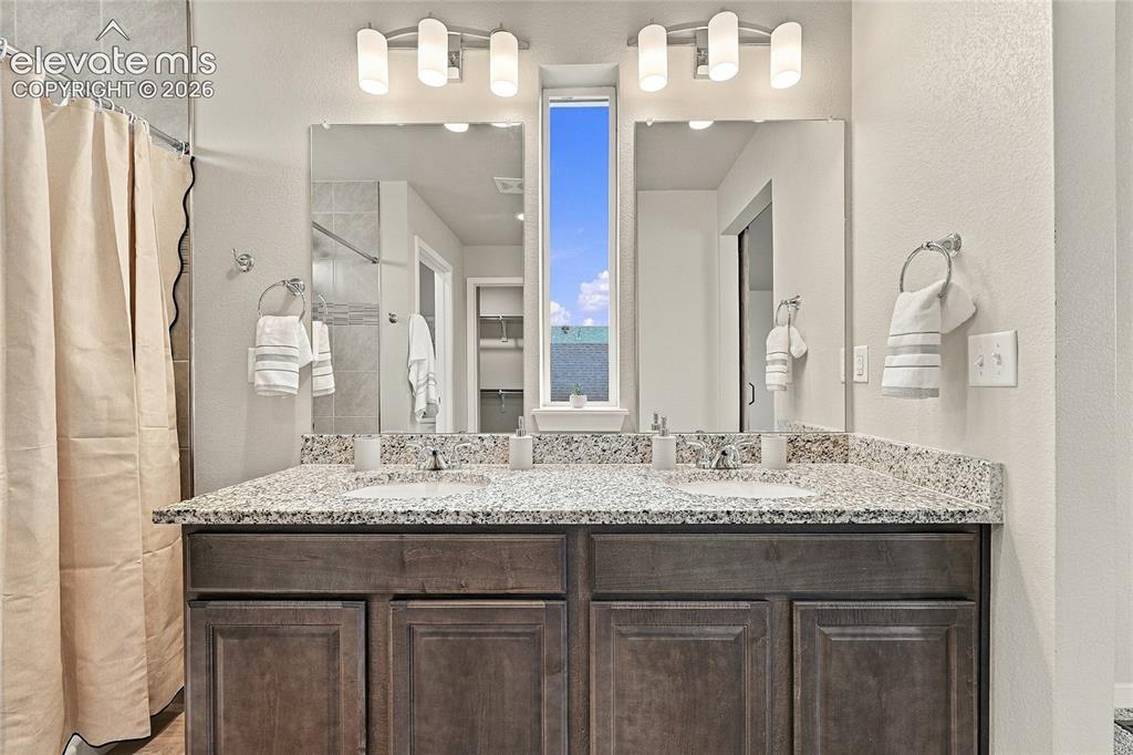 Image 22 of 30: Dual vanity with integrated sinks, granite countertop, rich wood-finish cab