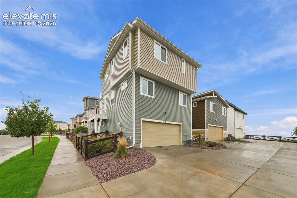 Image 25 of 30: Three-story residence featuring multi-tone siding and an attached garage