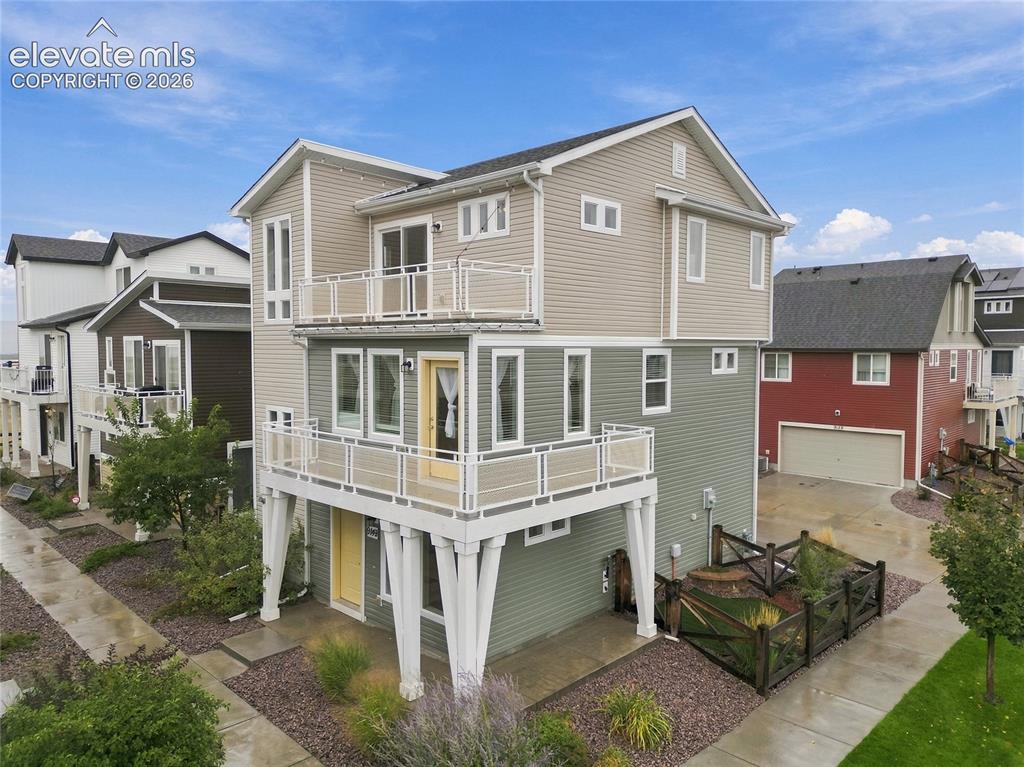 Image 26 of 30: Multi-level residence with two balconies featuring white railings, an eleva